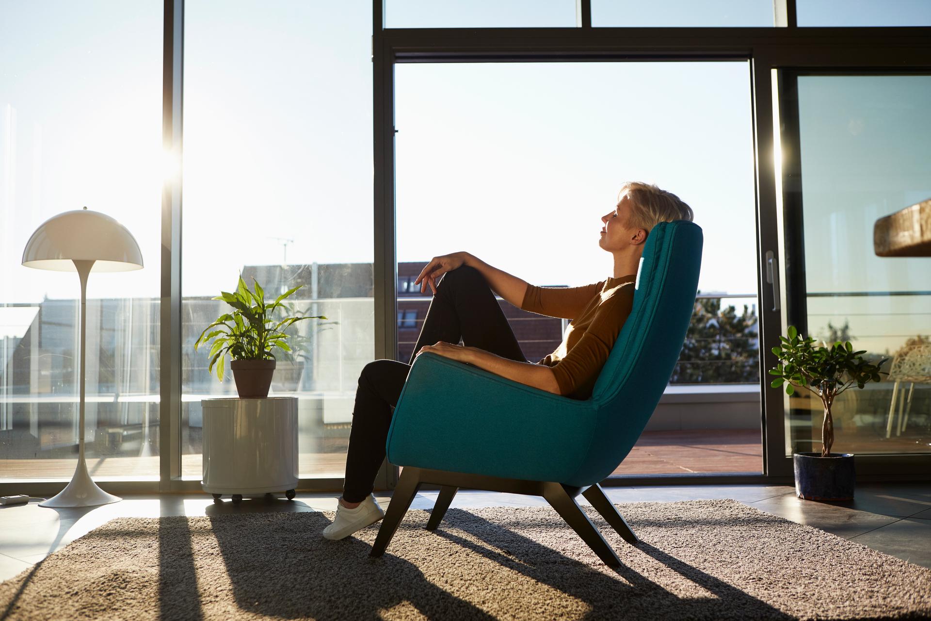 Woman sitting in armchair in sunlight with closed eyes