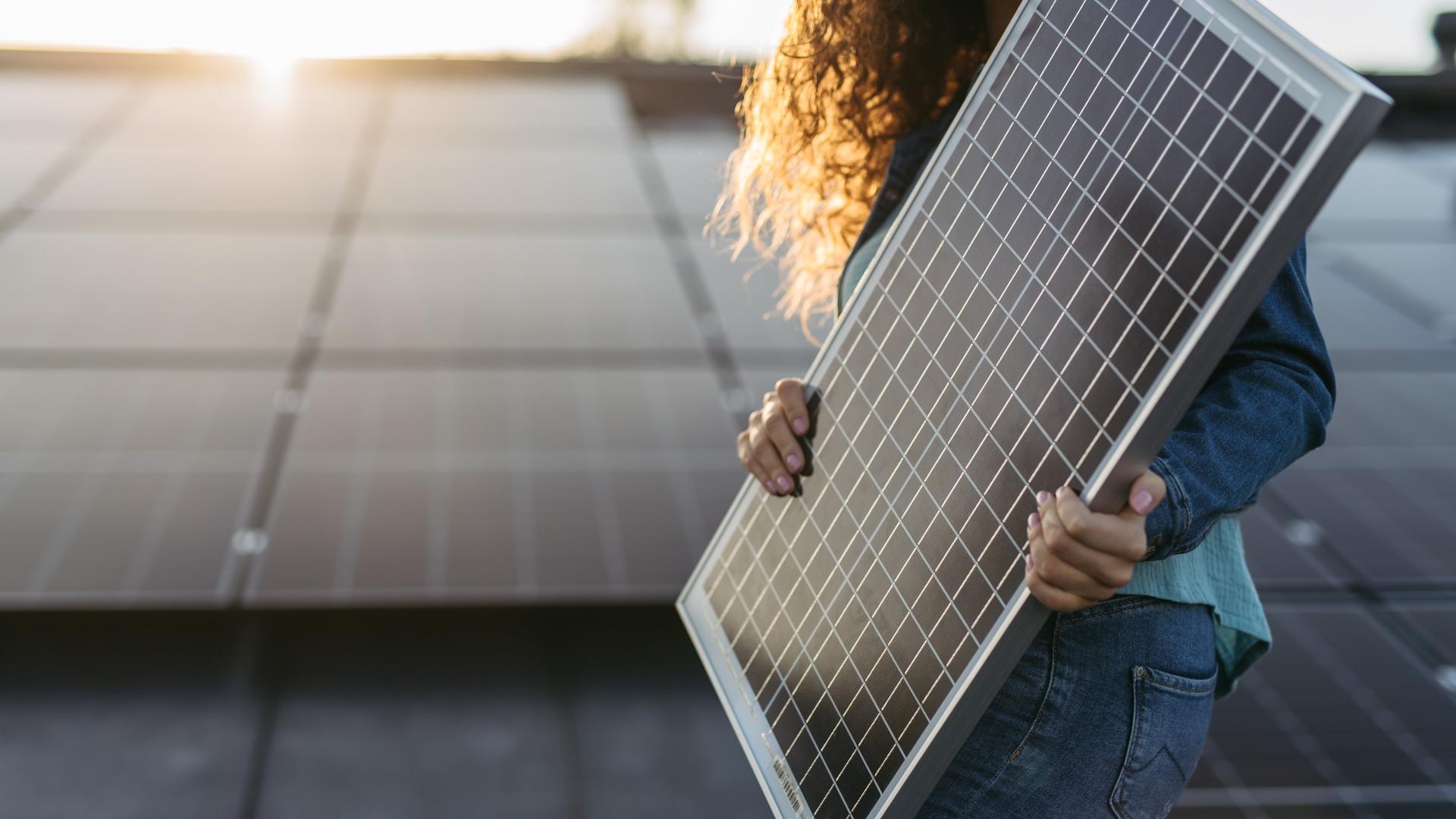Close up of a woman holding solar panel on the roof with photovoltaics panels.
PV
Photovoltaik
