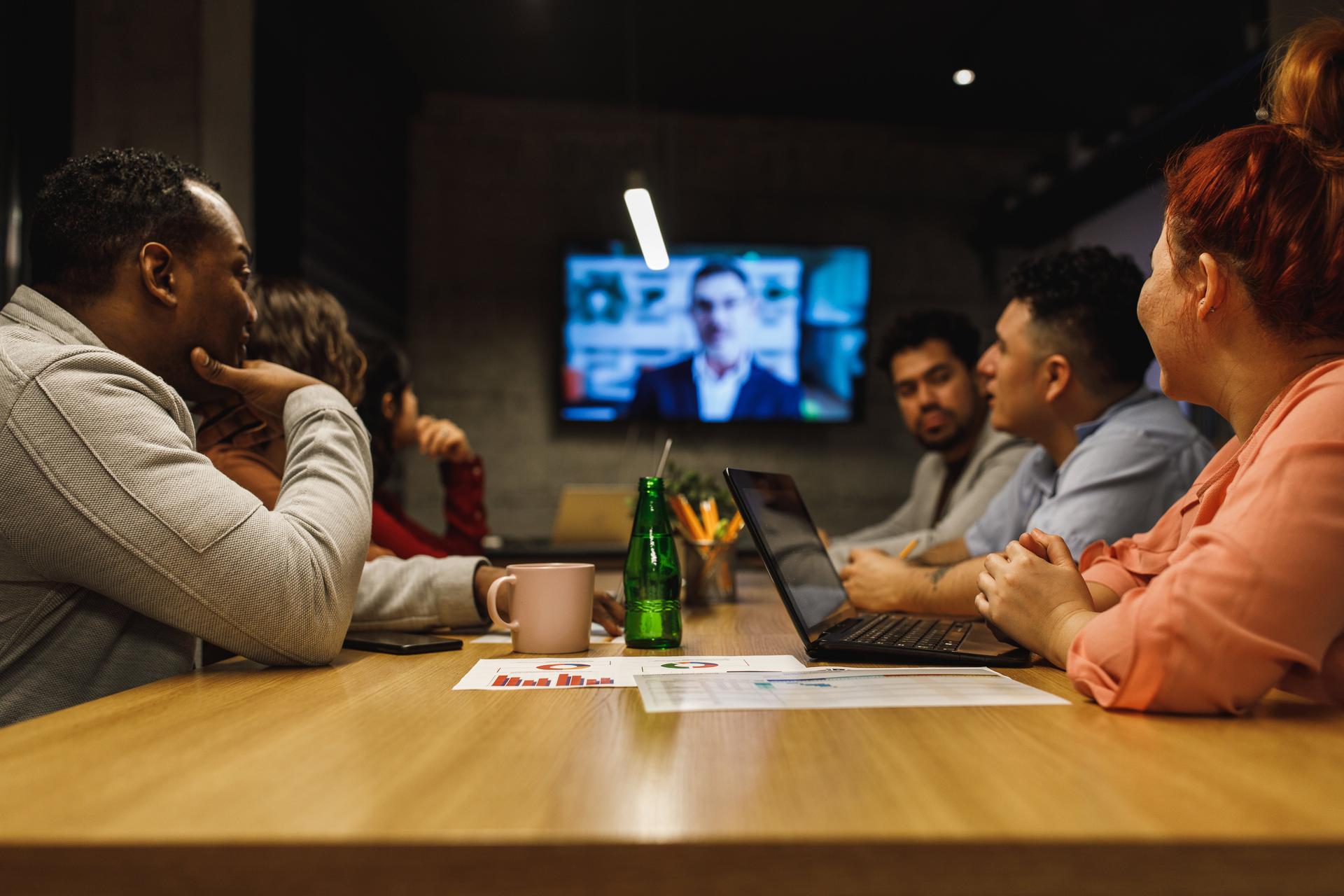 Low angle view of a multi-ethnic group of office workers paying attention to his supervisor who is doing a videoconference to update team about upcoming strategies.